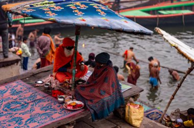 A Hindu Monk sitting on the bank of Ganges river in Varanasi Ghat during Kumbha mela. Benaras Utrar Pradesh India 01/05/2024 clipart