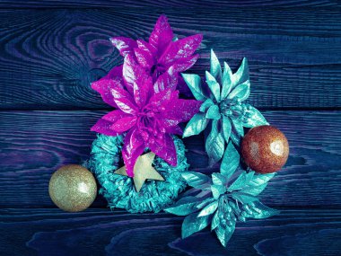 Noel süsleri. Koyu ahşap arka planda yeni yıl süslemeleri. Noel süsü olarak mavi renkli çelenkler, toplar, yıldızlar ve oyuncaklar. Kutlama kartpostalı. Seçici yumuşak odak