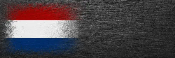 stock image Flag of Netherlands. Flag is painted on black slate stone. Stone background. Copy space. Textured creative background