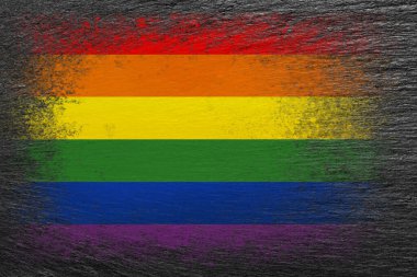 LGBT bayrağı. Bayrak siyah taşın üzerine boyanmıştır. Taş zemin. Yapılandırılmış yaratıcı arkaplan