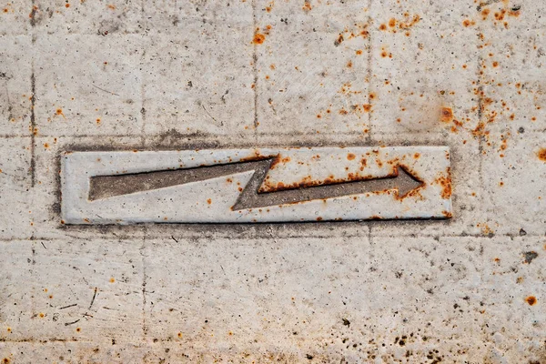 Lightning sign. Metal rusty arrow. Electricity sign on the sidewalk. Warning sign on the pavement