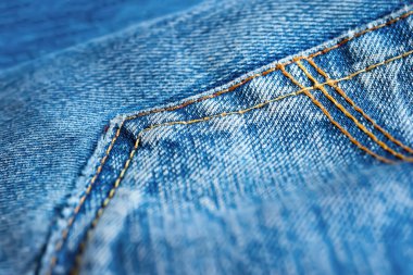 Jeans background. Denim fabric with yellow seam pocket. Selective soft focus