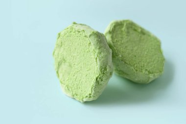 Marshmallows on blue. Green divided marshmallow on a blue background. Two halves of marshmallows. Colored sweetness