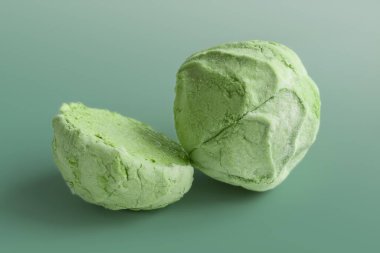 Marshmallow on green. Green divided marshmallow on a green background. Two halves of marshmallows. Colored sweetness