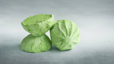 Green marshmallow. A whole and two halves of a green marshmallow on a gray abstract background. Sweet dessert. Colored sweetness