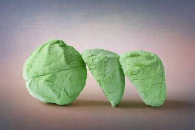 Marshmallows on an abstract background. A whole and two halves of a green marshmallow. Sweet dessert. Colored sweetness