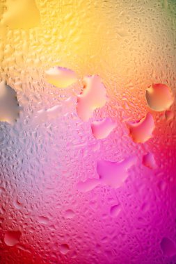 Abstract background. Abstract blur image of yellow and pink soft gradients and highlights through wet glass. Texture of water drops on frozen glass. Creative background