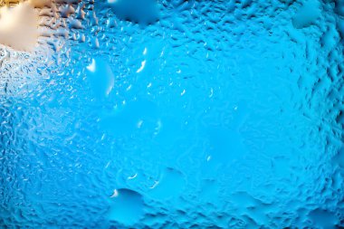 Abstract background. Abstract blur image of blue soft spots and gradients through wet glass. Texture of water drops on glass. Creative background. Horizontal layout