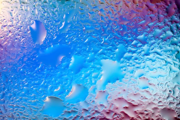 Abstract background. Abstract blurred image of colored soft spots and gradients through transparent wet glass. The texture of water drops on glass. Creative backdrop