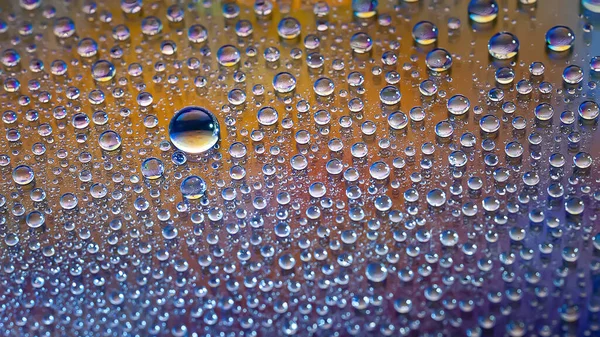 Drops of water. Texture of the drops. Abstract gradient background. Multicolored blue-gold iridescent gradient. Heavily textured image. Shallow depth of field. Selective soft focus