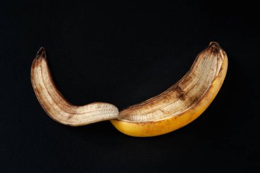 Banana peel on a black background. One overripe banana macro. Food waste