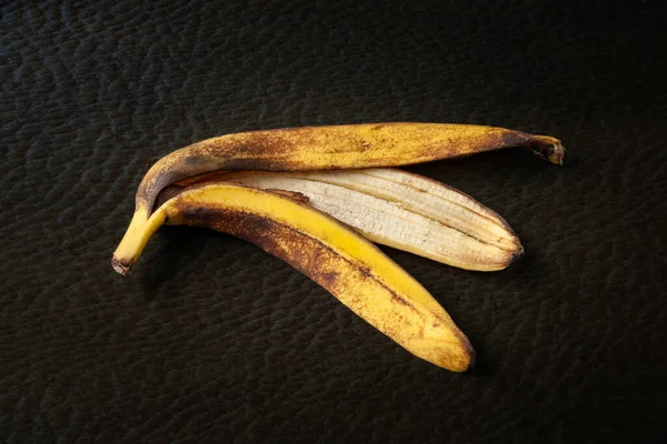 Banana peel. Peel of one overripe banana on a dark textural background close up. Food waste