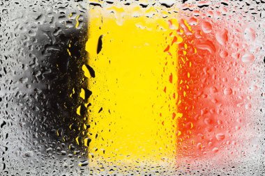 Belçika bayrağı. Su damlalarının arka planında Belçika bayrağı var. Yağmur damlalı bayrak. Cama sıçrıyor. Soyut arkaplan