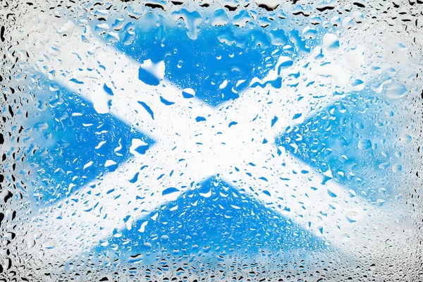 Flag of Scotland. Scotland flag on the background of water drops. Flag with raindrops. Splashes on glass. Abstract background