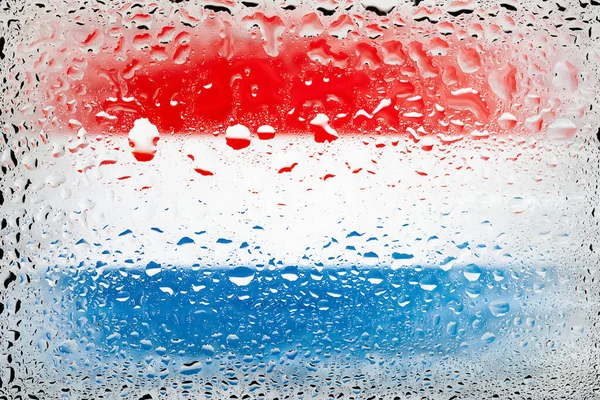 Flag of Netherlands. Netherlands flag on the background of water drops. Flag with raindrops. Splashes on glass. Abstract background