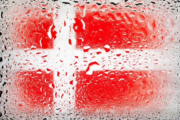 Flag of Denmark. Denmark flag on the background of water drops. Flag with raindrops. Splashes on glass. Abstract background