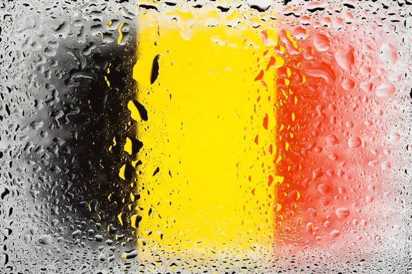 Flag of Belgium. Belgium flag on the background of water drops. Flag with raindrops. Splashes on glass. Abstract background