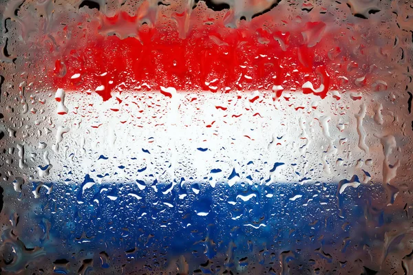 Netherlands flag. Netherlands flag on the background of water drops. Flag with raindrops. Splashes on glass. Abstract background