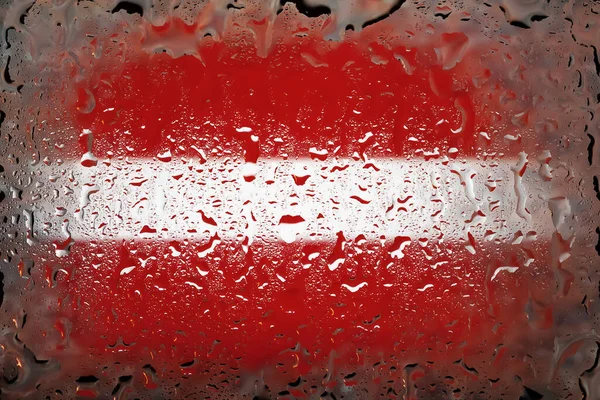 Latvia flag. Latvia flag on the background of water drops. Flag with raindrops. Splashes on glass. Abstract background