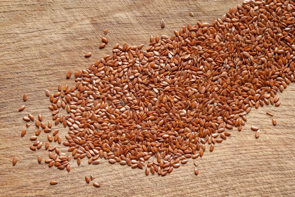 Flax seeds. Heap of flax seeds are scattered on a wooden board. Omega 3. Healthy food. Top view