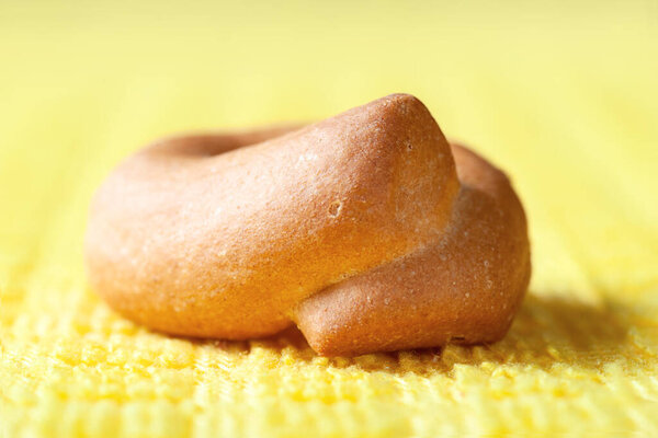 Bagel close-up. One small dry bagel on yellow. Selective soft focus