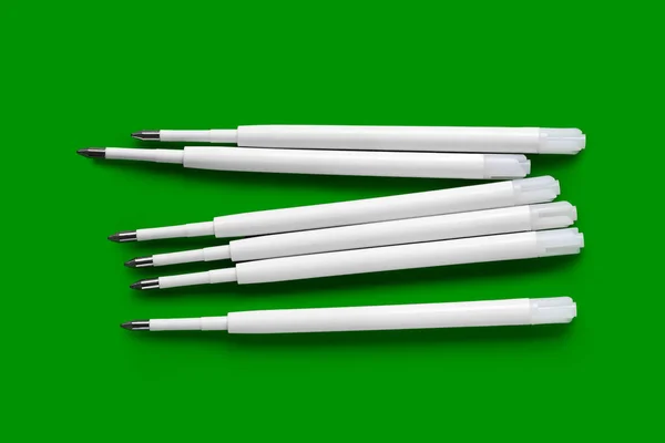 Refills for a ballpoint pen. Plastic rods for a ballpoint pen. White ink refills on a green background