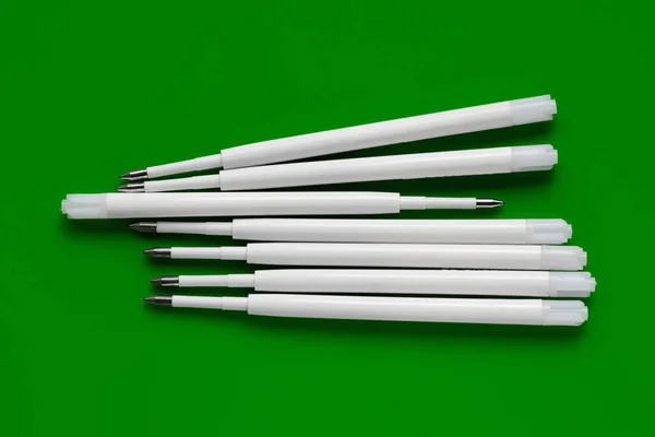Plastic refills for ballpoint pens. Ballpoint pen refills. White ink refills on a green background