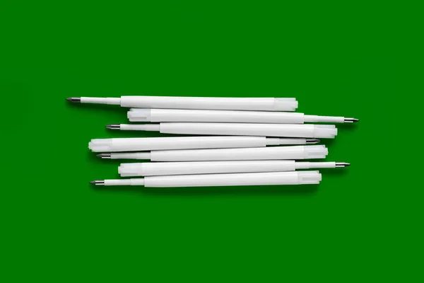 Plastic refills for ballpoint pens. Refills for a ballpoint pen. White ink refills on a green background
