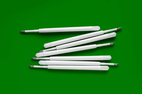 Plastic rods for a ballpoint pen. Refills for a ballpoint pen. White ink refills on a green background