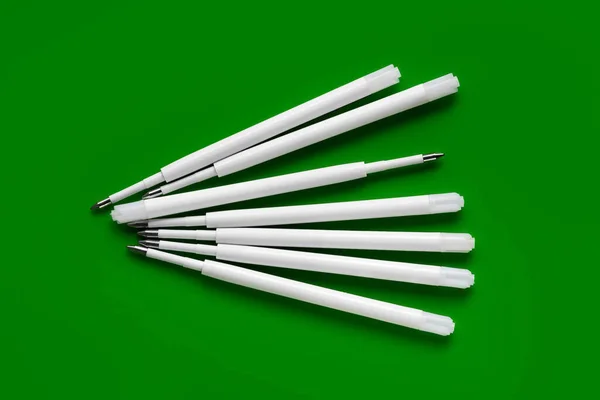 Plastic rods for a ballpoint pen. Ballpoint pen refills. White ink refills on a green background
