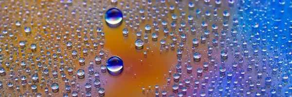 Water drops banner. Droplet texture. Abstract gradient backdrop Multicolored blue-gold rainbow gradient. Heavily textured image. Shallow depth of field. Selective soft focus