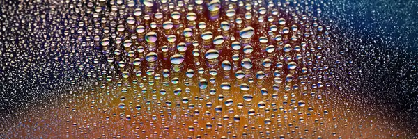 Water drops banner. Many drops abstract background. Colored drop texture. Rainbow gradient. Heavily textured image. Shallow depth of field. Selective soft focus
