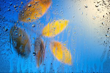 Pencerede yağmur damlaları. Cama su damlıyor. Soyut arkaplan. Yeşil yapraklar. Damlaların dokusu. Seçici yumuşak odak