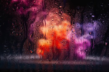 Pencerede yağmur damlaları. Bardağa bir damla su. Soyut arkaplan. Çok renkli duman. Dokusunu düşürür. Seçici yumuşak odak