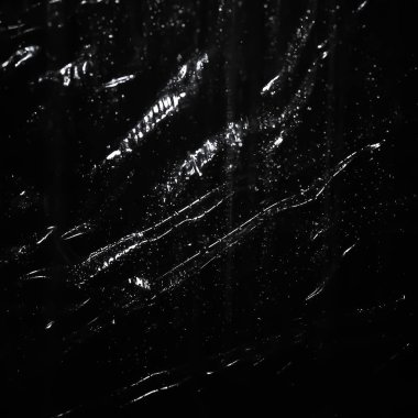 Soyut arkaplan. Islak polietilen parıltısı. Siyaha sentetik sim. Seçici odak