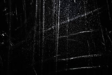 Abstract background. The shine of crumpled polyethylene. Synthetic glitter on black. Selective focus