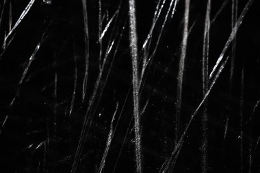 Abstract background. The shine of wet, crumpled polyethylene. Synthetic shine on black. Selective focus