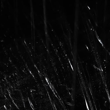 Abstract background. Polyethylene shine. Glittering drops. Synthetic glitter on black. Selective focus