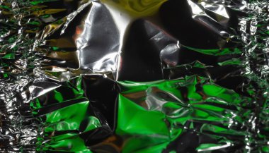 Parlak yüzey. Buruşmuş alüminyum folyo. Buruşuk arka plan. Karanlıkta renkli bir parıltı. Seçici yumuşak odak