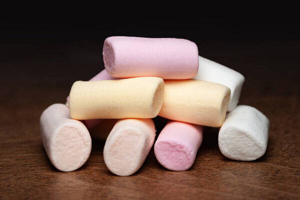 Marshmallow. A pile of colored mini marshmallows on a wooden surface. Selective soft focus