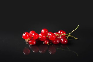 Kırmızı çilek. Frenk üzümü. Koyu arkaplandaki kırmızı böğürtlenlerin yakın çekimi. Yumuşak odak