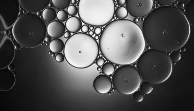 Yağ kabarcıkları. Sudaki yağ baloncuklarına yakın çekim. Siyah ve beyaz tonlarda soyut doku. Makro fotoğrafçılık