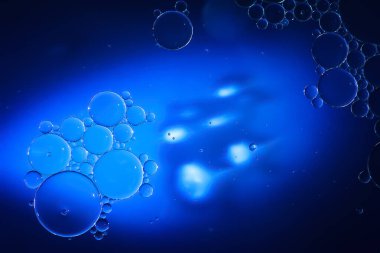 Yağ kabarcıkları. Sudaki yağ baloncuklarına yakın çekim. Koyu mavi renklerde soyut doku. Makro fotoğrafçılık