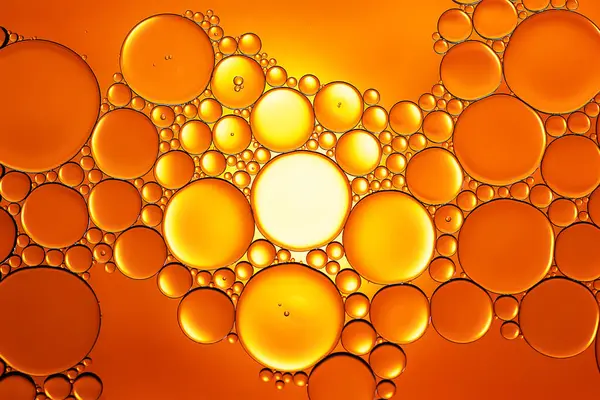 Yağ kabarcıkları. Sudaki yağ baloncuklarına yakın çekim. Altın tonlarda soyut dokular. Makro fotoğrafçılık