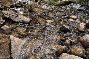 Dağ nehri. Hızlı hareket eden suda büyük kayalar. Islak taş dokusu. Dağlarda seyahat et.