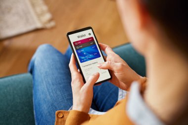 Close up of latin woman hand using smartphone to check the balance of her digital online wallet. Hispanic woman using mobile phone checking payments, account statement and transaction history of her credit cards. Checking expenses of the month on sma clipart