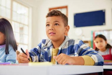 Latin kökenli liseli çocuk ilkokulda okumaya dikkat ediyor. Karışık ırk çocuğu konsepti ve okulda dinleme öğretmenini anlıyor. Çok ırklı sınıf arkadaşlarının arka planda masalarda oturduğu çalışmalara odaklanan ilk çocuk.