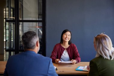 İş görüşmesi sırasında gülümseyen mutlu bayan aday. Çinli iş kadını, bir şirket ortamında mülakatçılarla görüşüyor. İş görüşmesi sırasında Asyalı genç bir kadınla konuşan insan kaynakları yöneticileri..