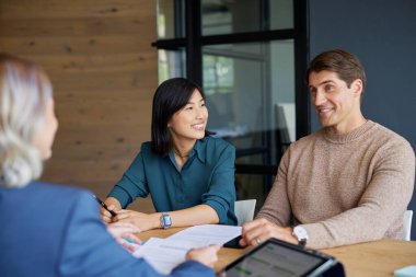 Genç melez çift danışmanımızla finansal planlarımızı tartışıyor. Yatırım stratejilerinde çok ırklı çifte rehberlik eden kadın finans danışmanı. Çinli kadın ve orta yaşlı adam yatırım için banka müdürüyle görüşüyor..