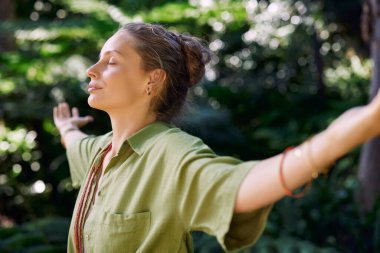Huzurlu kadın kollarını açıyor ve gözleri kapalı bir şekilde uzanıyor, bir orman inzivasının temiz havasını ve huzurunu kucaklıyor. Kadın derin nefes alıp veriyor, kendisiyle ve doğayla derin bir bağ hissediyor. Kız dinginlikten ve ateşten hoşlanıyor.